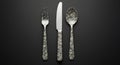 A set of cutlery consisting of a fork, knife, and spoon is arranged vertically against a Royalty Free Stock Photo