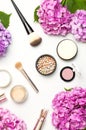 Set of decorative cosmetics mascara powder lipstick eyeshadow blush makeup brush pink hydrangea flowers on light background top Royalty Free Stock Photo