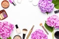 Set of decorative cosmetics mascara powder lipstick eyeshadow blush makeup brush pink hydrangea flowers on light background top Royalty Free Stock Photo