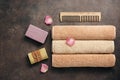 A set of different bath accessories, terry towels roll, wooden comb, handmade soap on a dark brown rustic background decorated Royalty Free Stock Photo