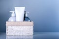 Set of different beauty products in basket on blue background.