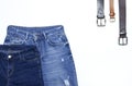 Set of different blue jeans and leather belts isolated on white background top view flat lay. Detail of nice blue jeans