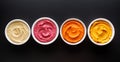 Set of different colorful hummus: classic, beetroot, pepper and pumpkin on a black background