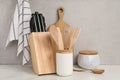 Set of different kitchen utensils on white near gray wall