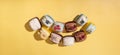 Set of different macaroons on yellow background top view, flat lay. Delicious luxury food aesthetics.