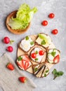 Set of different sandwiches with cheese, radish, lettuce, strawberry, sprats, tomatoes and cucumber on wooden board on a gray Royalty Free Stock Photo