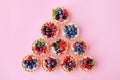 Set of different tartlets or cake with cream cheese, honey and summer berry on pink. Pastry dessert from above. Flat lay