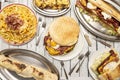 Set of dishes with wild food, big hamburger with egg, fried bacon and melted cheese, sandwich with the same ingredients, fries