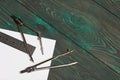 Set for drawing. Two compasses, a metal ruler and a sheet of white paper. They lie on pine boards painted in black and green Royalty Free Stock Photo