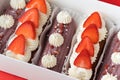 Set of eclairs with chocolate glaze, decorated with strawberries and whipped cream cheese topping. Traditional french dessert in a Royalty Free Stock Photo