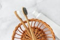 Set of eco-friendly toothbrushes, toothpaste in straw basket on marble background.