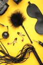 Set of erotic toys for BDSM on yellow background. The game of sexual slavery with a whip, gag and leather blindfold. Intimate sex Royalty Free Stock Photo