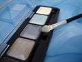 Set of eyeshadows and applicator brush on blue Royalty Free Stock Photo