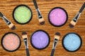 Set of 5 eyeshadows and brushes over wooden texture close-up Royalty Free Stock Photo