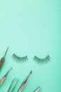 Set of false eyelashes extencions on mint background with tweezers. Minimalism. Verctical photo Royalty Free Stock Photo