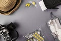 Set for flight small bottles with cosmetics, camera, hat, earplugs, medicine, air ticket and documents on gray background. Top