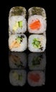 Set of four classic sushi rolls isolated on black backround with reflection. Salmon, avocado, eel, cucumber, sesame Royalty Free Stock Photo