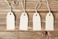 set of four tags hanging on rope on wooden background Four paper blank tags with rope on wooden background.