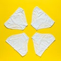 Set of four white women`s panties on a bright yellow background. Flat lay. Royalty Free Stock Photo