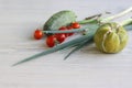 Set of fresh garden vegetables. Green cucumber, red cherry tomatoes, green Chives. Set with raw food on white wooden background. Royalty Free Stock Photo