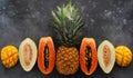 Set of fresh juicy tropical fruits lying on a concrete background, pineapple, papaya, melon and mango, top view, banner