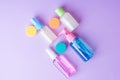 Colorful travel size bottles with cosmetics on lavender background.