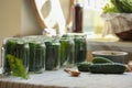 Set of glass jars with fresh cucumbers and other ingredients prepared for canning on table Royalty Free Stock Photo