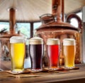 Set of glasses of different beer on wooden table and blurred copper brewing system at the background Royalty Free Stock Photo