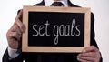 Set goals motivation written on blackboard in businessman hands, success tips