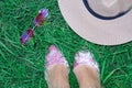 Set on the grass, women`s legs in shoes, glasses in the form of a heart and a hat.