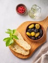 A set of green and black dried olives in bowl with fresh ciabatta slices on a light background with olive oil and basil close up Royalty Free Stock Photo