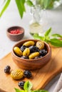 A set of green and black dried olives in bowl on a light background with olive oil and basil close up. The concept of vegetarian Royalty Free Stock Photo