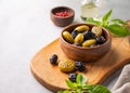 A set of green and black dried olives in bowl on a light background with olive oil and basil close up. The concept of vegetarian Royalty Free Stock Photo