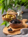 A set of green and black dried olives in bowls on a wooden cutting board on a dark background with olive oil and eucalyptus branch Royalty Free Stock Photo