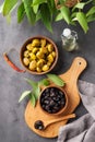 A set of green and black dried olives in bowls on a wooden cutting board on a dark background with olive oil and eucalyptus branch Royalty Free Stock Photo