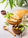 A set of green and black dried olives in wooden bowl with fresh chiabatta bread on a light background with olive oil and basil Royalty Free Stock Photo