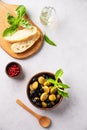 A set of green and black dried olives in wooden bowl with fresh chiabatta bread on a light background with olive oil and basil. Royalty Free Stock Photo