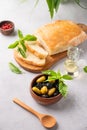 A set of green and black dried olives in wooden bowl with fresh chiabatta bread on a light background with olive oil and basil Royalty Free Stock Photo