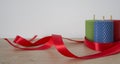 Set of colorful honey beeswax candles with red ribbon on wooden table with white background. Banner with copy space