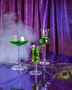 Set of green cocktails with absinthe on a purple background and smoke. Royalty Free Stock Photo