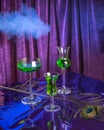 Set of green cocktails with absinthe on a purple background and smoke.
