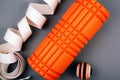 Set of green fascia release ball, orange bumpy foam massage roller for trigger points and belt over grey background
