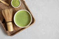 Set with green matcha tea, bamboo whisk and matcha powder in a wooden tray on a gray background. Japanese traditional tea. View Royalty Free Stock Photo