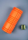 Set of green fascia release ball, orange bumpy foam massage roller for trigger points over grey background