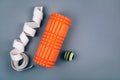 Set of green fascia release ball, orange bumpy foam massage roller for trigger points and belt over grey background