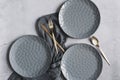 set of grey modern ceramic plates with golden cutlery.