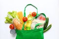 Set of grocery items from vegetables, canned food, pasta, oil, cereal in green eco shopping bag on white background. Top
