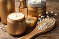 Set of hair cosmetic products, brush and flowers on wooden table, closeup Royalty Free Stock Photo
