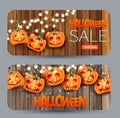 Set of halloween sale banner cards with creepy pumpkin faces and glowing garland lights over wooden board background. Royalty Free Stock Photo