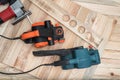 Set of handheld woodworking power tools for woodworking and the workpiece lies on a light wooden background. Directly above